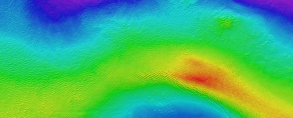 Wave ripples have parallel crests on bathymetry maps and show a quite regular pattern. They mostly occur in shallow areas, as they need strong wave currents to form. Here, the wave ripples are 15-20 cm high and a few hundred meters long. Bathymetry data from MAREANO/Kartverket.