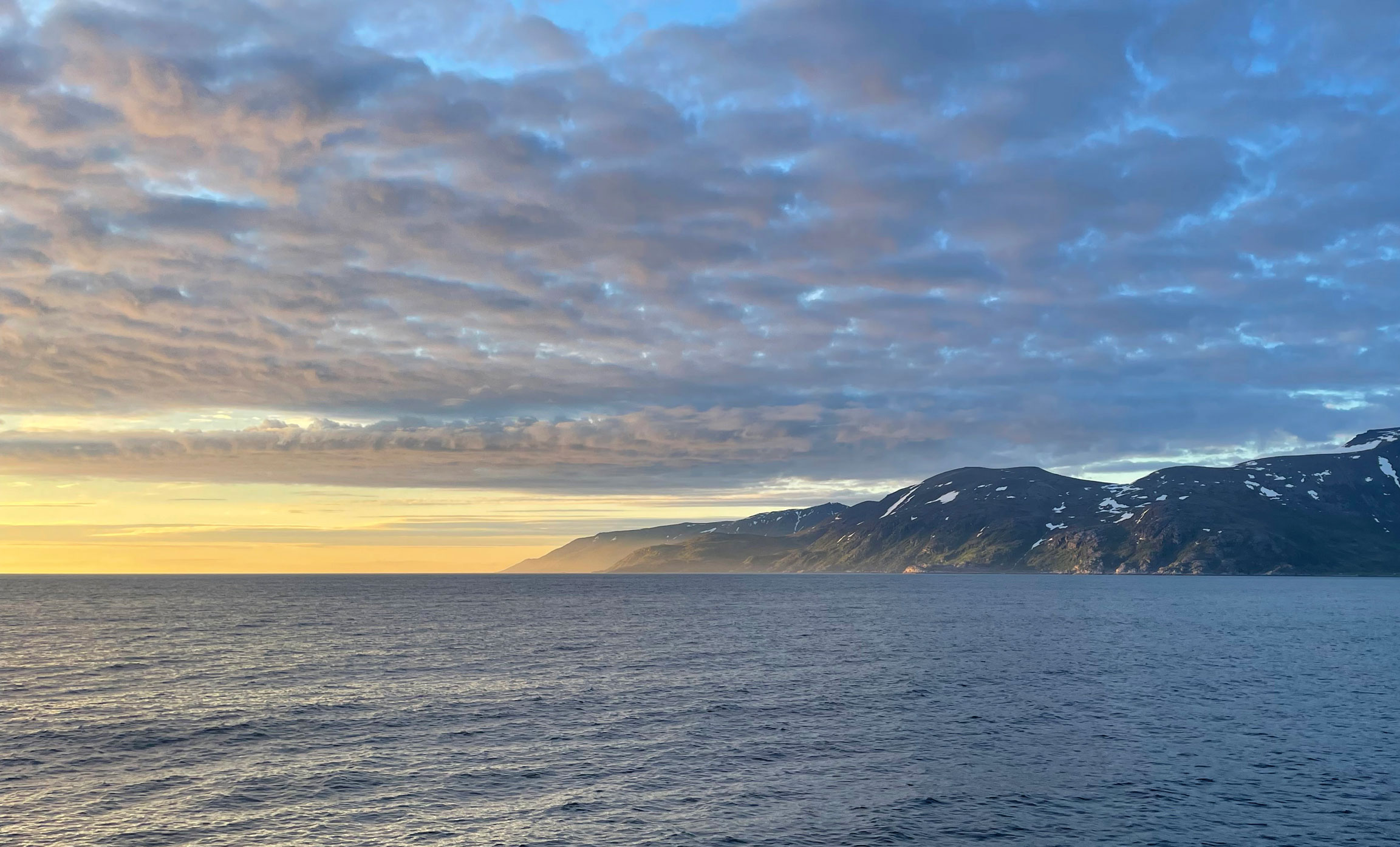 Utsiktsbilde med fjell, sjø og sol.