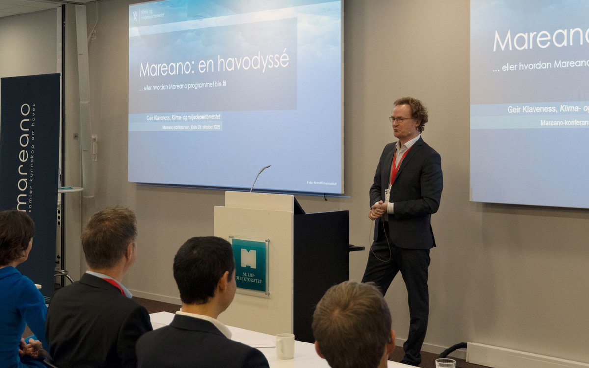 Ein mann står foran publikum og snakkar.