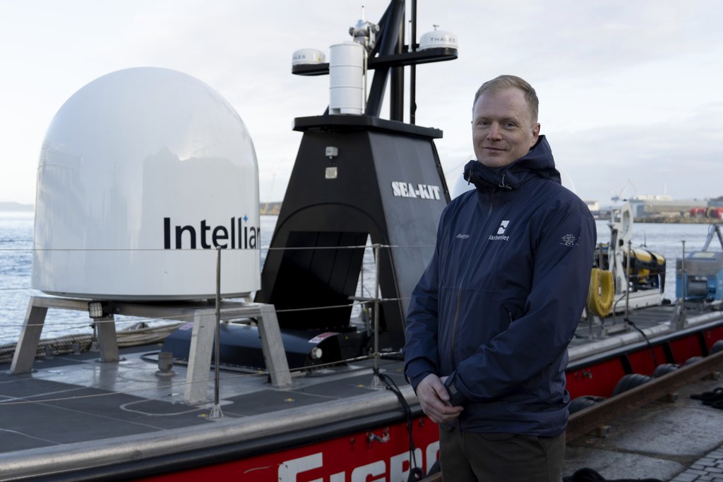 En mann står foran en stor USV i havna i Stavanger.